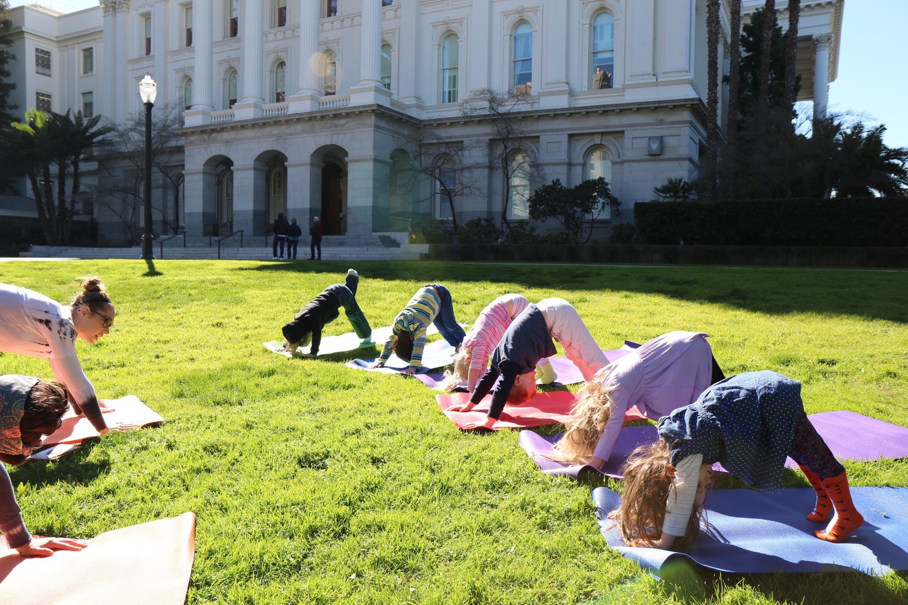 Preschoolers in an outdoor downward-dog yoga pose during a Reggio-inspired learning session at Growing Mindfully Sacramento.